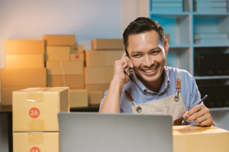 Homem atendendo o telefone em frente ao computador