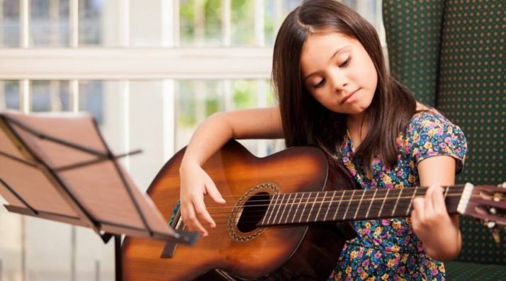 criança ensaindo violão