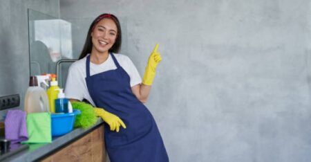 mulher com luva de limpeza, avental e produtos de limpeza