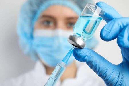Profissional da área da saúde com seringa e ampola