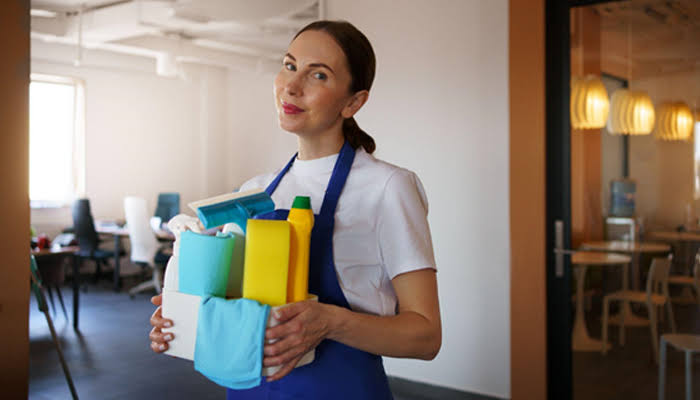 Mulher com uniforme de limpeza e produtos de limpeza