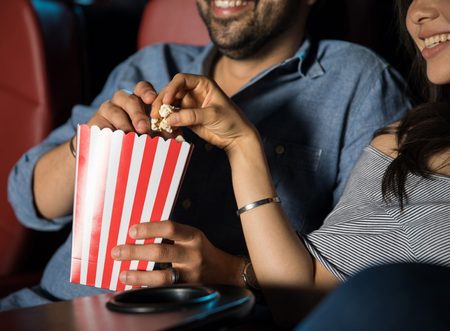 Homem e mulher no cinema comendo pipoca