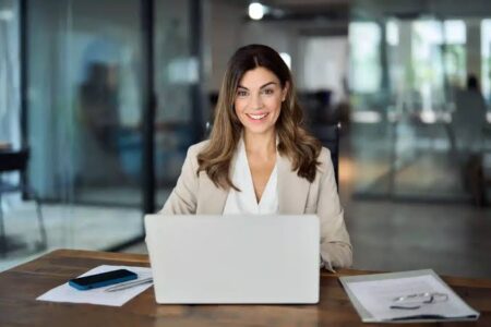 Mulher em frente ao notebook com sorriso descontraido